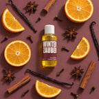 kaisa WINTERZAUBER Saunaaufguss, 100-ml-Flasche mit Orangenscheiben und Gewürzen auf braunem Hintergrund